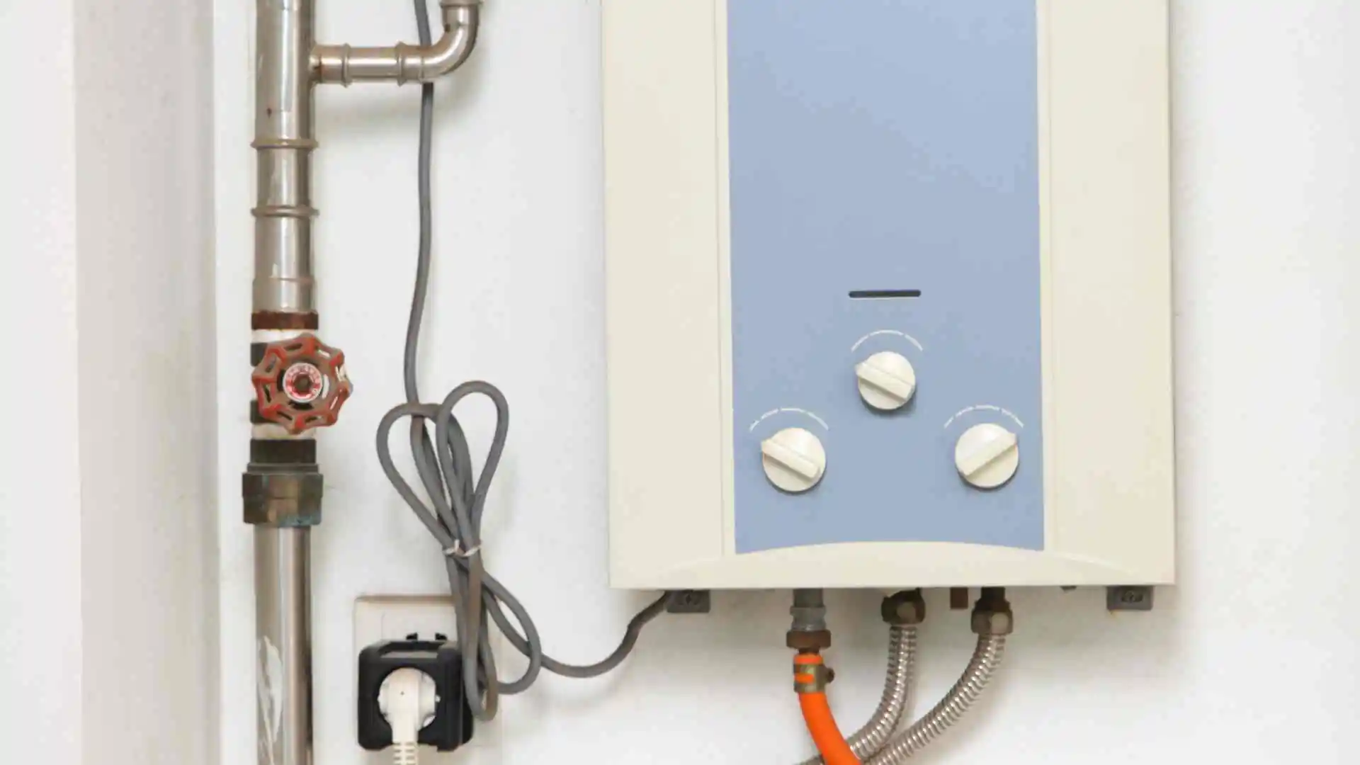 Tankless water heater mounted on a wall with its water lines and shutoff valve